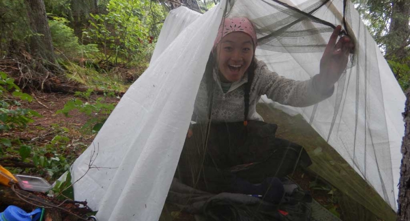 a person smiles from under a shelter in a wooded area